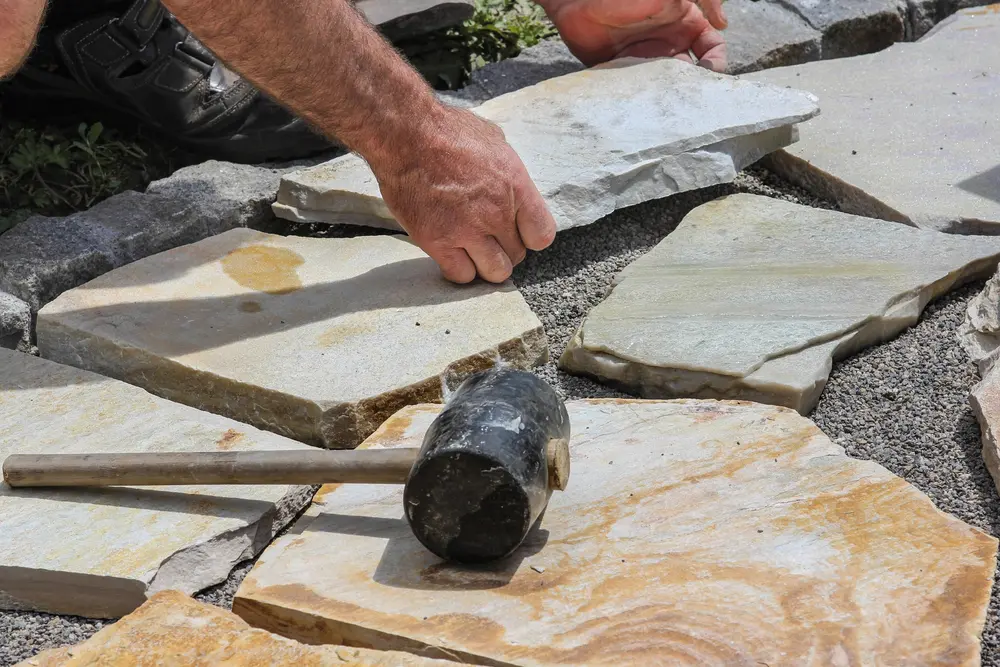 Man making a patio out of flagstone, one of the most popular types of pavers