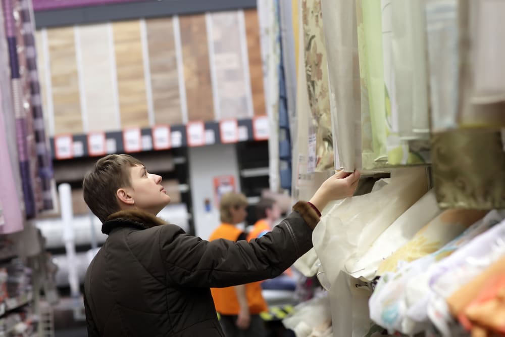 Guy picking out custom curtains in a store for a piece on types of curtains for your home