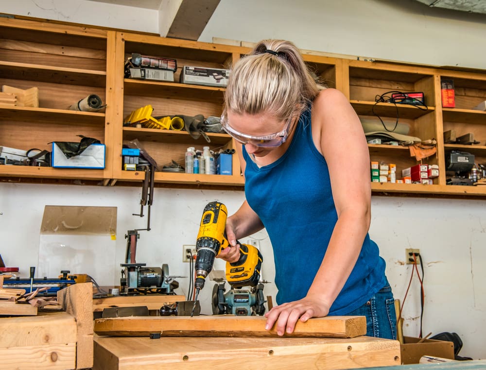 Lady using common types of power tools in a home garage